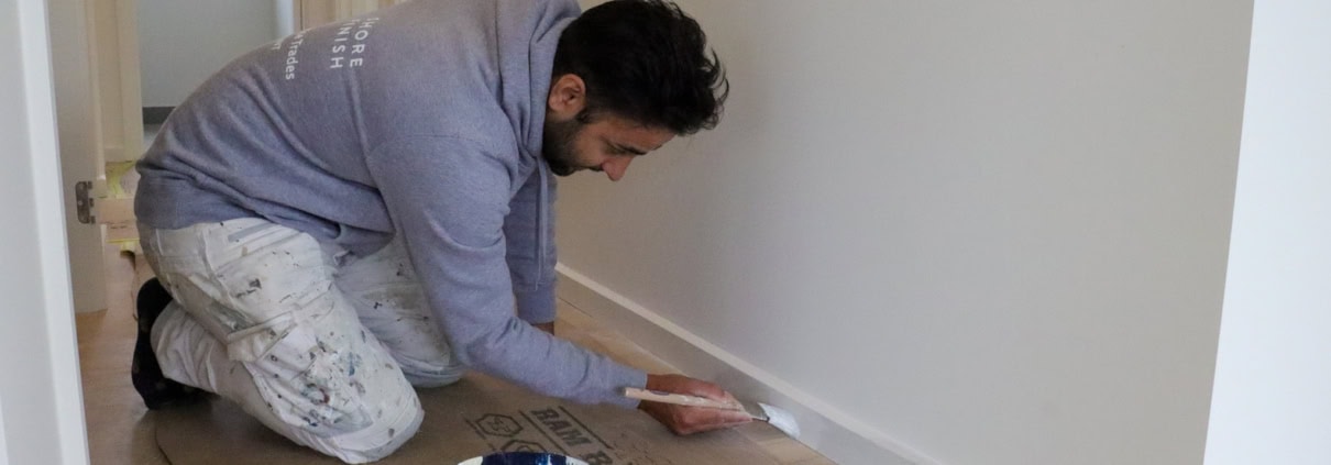Shore Finish painter cutting in a skirting board inside a Geelong home